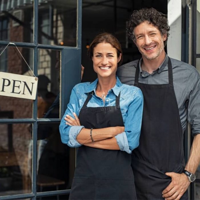 couple in front of a business with the sign open